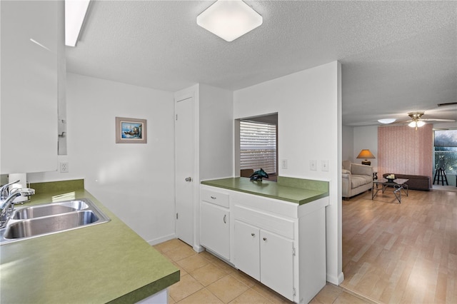 kitchen with white cabinets, sink, ceiling fan, light tile patterned floors, and a textured ceiling