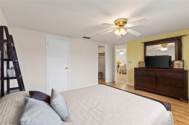 bedroom with a textured ceiling, light hardwood / wood-style flooring, and ceiling fan