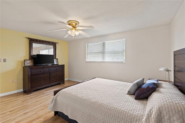 bedroom featuring ceiling fan, light hardwood / wood-style floors, and a textured ceiling