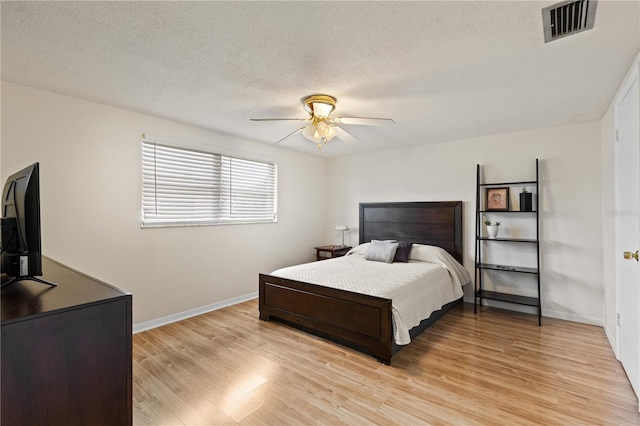 bedroom featuring ceiling fan, light wood-type flooring, and a textured ceiling