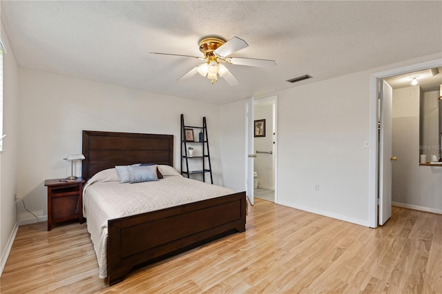 bedroom with a textured ceiling, light wood-type flooring, ensuite bathroom, and ceiling fan