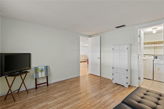 interior space with washing machine and clothes dryer and light wood-type flooring