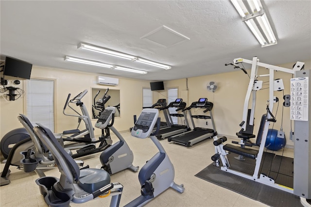 gym with a wall mounted air conditioner and a textured ceiling