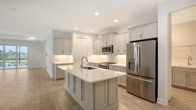 12649 Palatka Dr, Venice, FL 34293 - kitchen with sink, stainless steel appliances, decorative backsplash, and a center island with sink