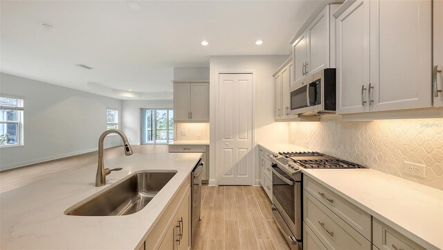 12649 Palatka Dr, Venice, FL 34293 - kitchen with appliances with stainless steel finishes, white cabinets, light hardwood / wood-style flooring, backsplash, and sink