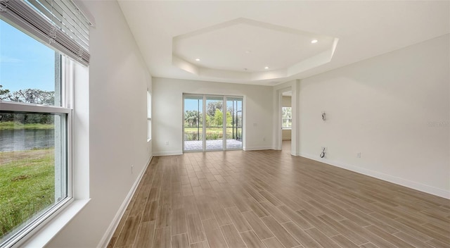 12649 Palatka Dr, Venice, FL 34293 - spare room featuring a tray ceiling, wood-type flooring, and plenty of natural light