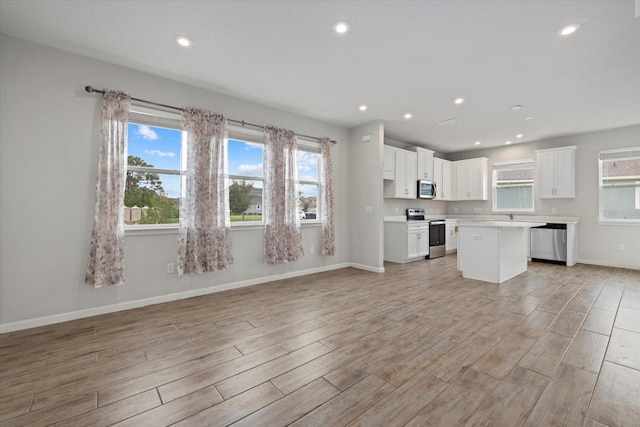 kitchen featuring white cabinets, a kitchen island, appliances with stainless steel finishes, and light hardwood / wood-style flooring