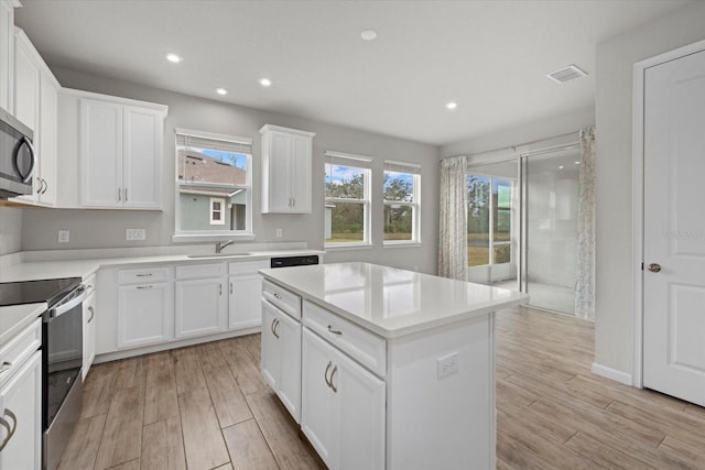 kitchen featuring white cabinetry, a kitchen island, stainless steel range with electric cooktop, and sink