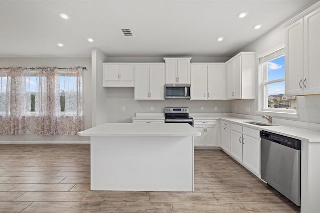 kitchen featuring sink, a kitchen island, white cabinets, and appliances with stainless steel finishes