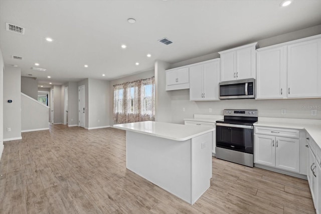 kitchen featuring white cabinets, a kitchen island, stainless steel appliances, and light wood-type flooring