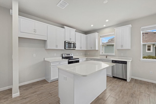 kitchen featuring sink, a wealth of natural light, a kitchen island, white cabinetry, and stainless steel appliances