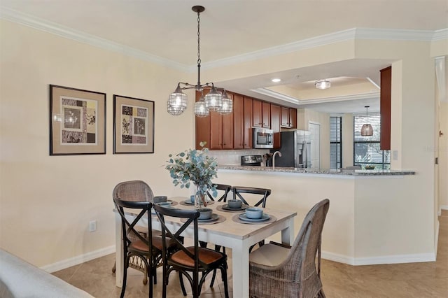 tiled dining room with a tray ceiling, crown molding, and sink