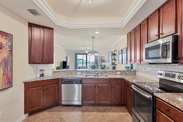 kitchen with sink, light stone countertops, appliances with stainless steel finishes, a notable chandelier, and kitchen peninsula