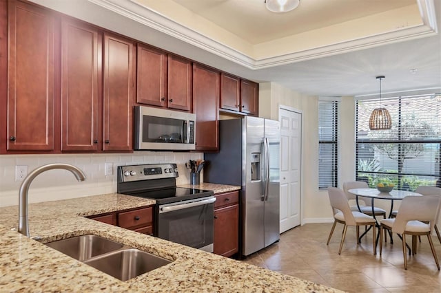 kitchen featuring light stone counters, sink, stainless steel appliances, and hanging light fixtures