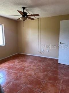 empty room with ceiling fan and a textured ceiling