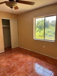 unfurnished bedroom with multiple windows, a closet, tile patterned floors, and ceiling fan