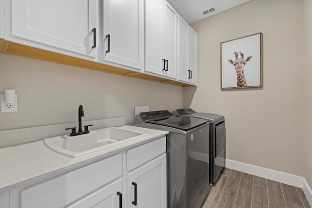 clothes washing area featuring sink, cabinets, and independent washer and dryer