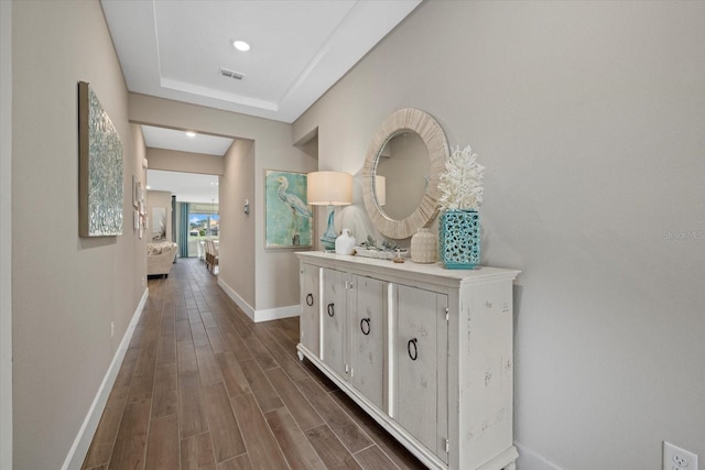 hallway featuring dark hardwood / wood-style flooring and a tray ceiling