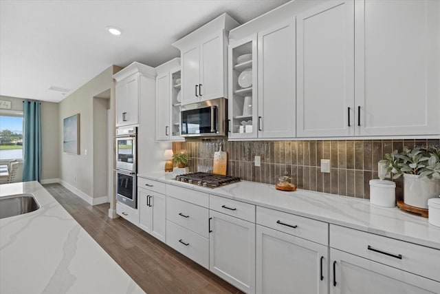 kitchen featuring white cabinets, appliances with stainless steel finishes, backsplash, and light stone counters