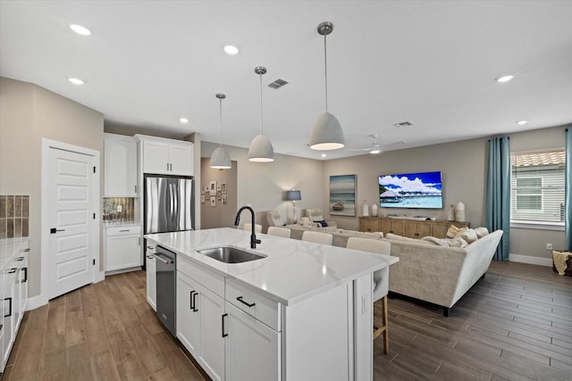 kitchen with sink, hanging light fixtures, an island with sink, white cabinets, and appliances with stainless steel finishes