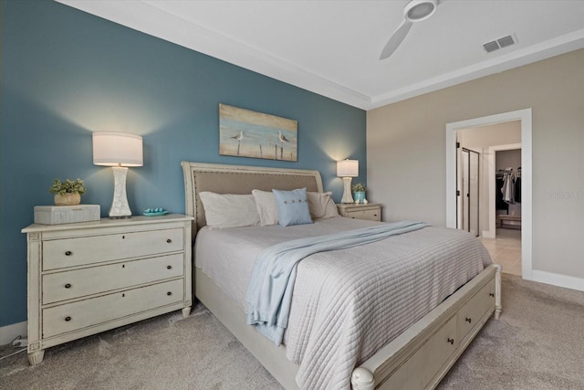 carpeted bedroom with a walk in closet, a closet, and ceiling fan