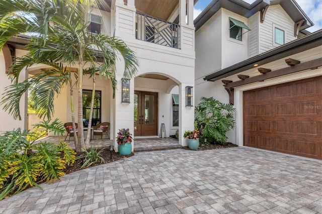 property entrance featuring a garage, a balcony, and french doors