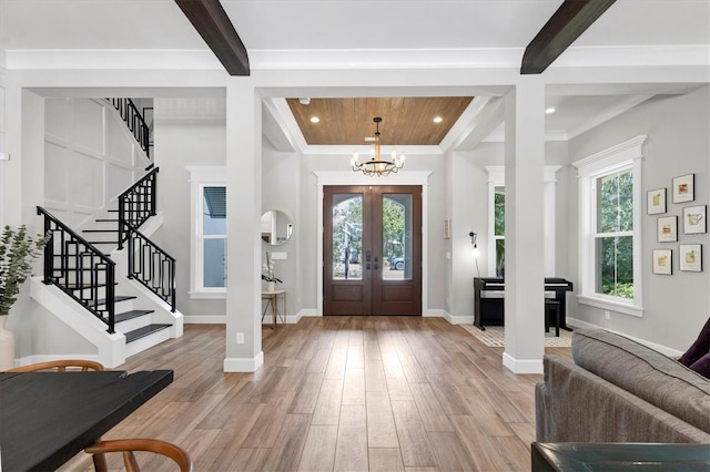 foyer featuring french doors, ornamental molding, light hardwood / wood-style flooring, beamed ceiling, and a chandelier