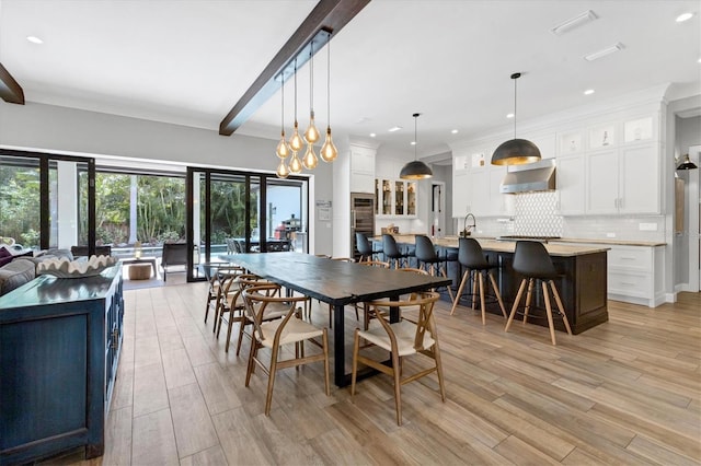 dining area featuring light hardwood / wood-style flooring, beamed ceiling, a notable chandelier, and sink