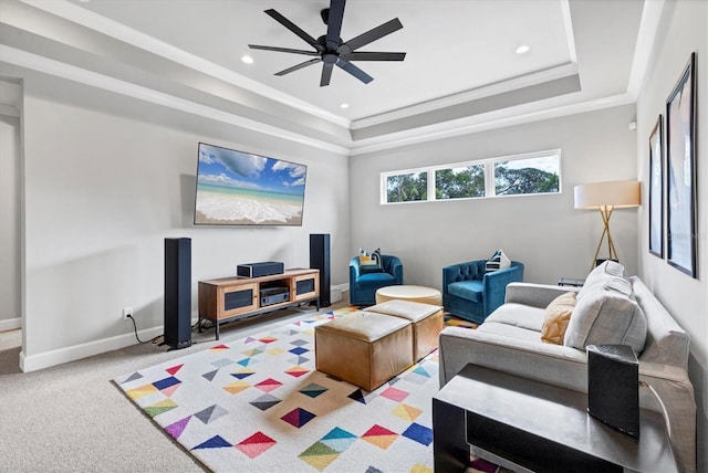 living room with carpet floors, a tray ceiling, ceiling fan, and crown molding