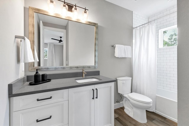 full bathroom featuring vanity, ceiling fan, hardwood / wood-style flooring, shower / bathtub combination with curtain, and toilet