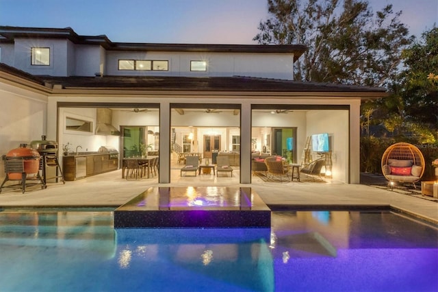 back house at dusk with an outdoor hangout area, a patio, and an outdoor kitchen