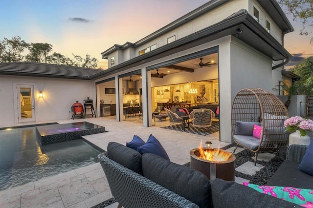 back house at dusk featuring a patio and an outdoor living space with a fire pit