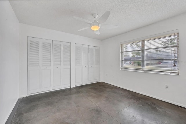 unfurnished bedroom with ceiling fan, multiple closets, and a textured ceiling