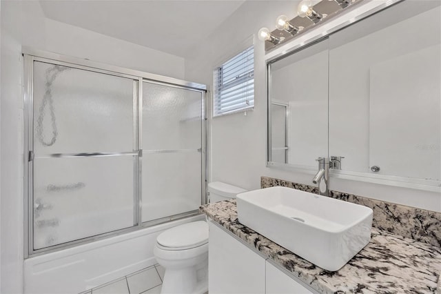 full bathroom featuring toilet, tile patterned flooring, vanity, and bath / shower combo with glass door