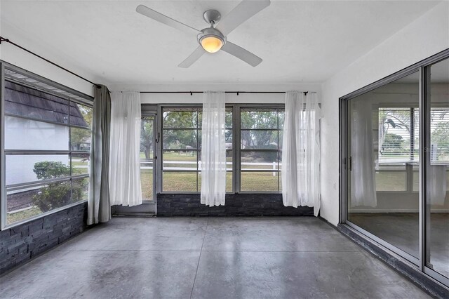 unfurnished sunroom featuring ceiling fan