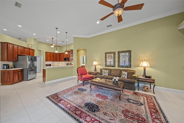 tiled living room with ceiling fan and ornamental molding