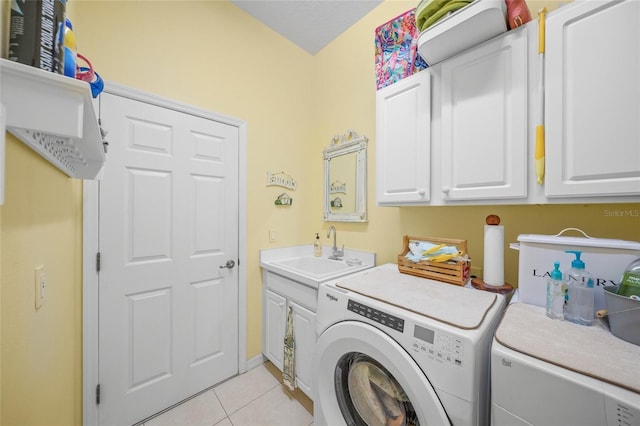 laundry area featuring washer and clothes dryer, cabinets, light tile patterned floors, and sink