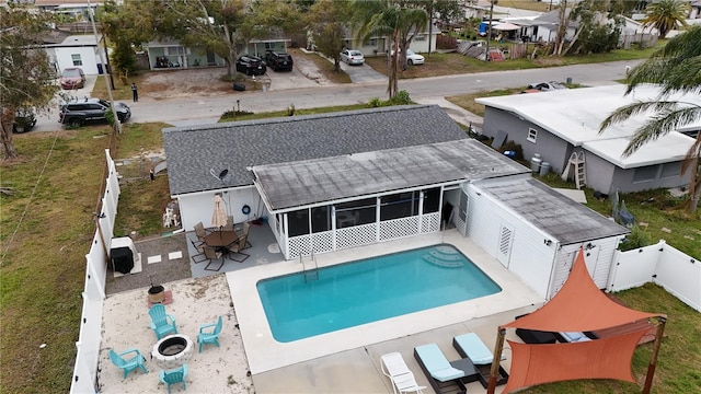 view of pool with a sunroom, a patio area, and a fire pit