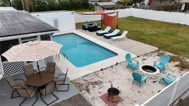 view of swimming pool with a patio, a yard, a storage unit, and an outdoor fire pit