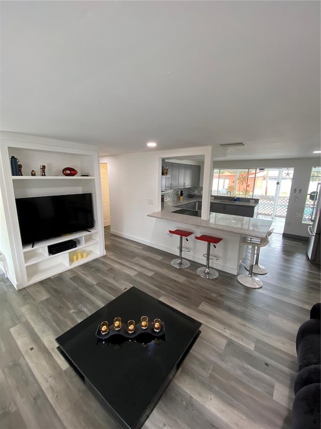 living room featuring built in shelves and wood-type flooring