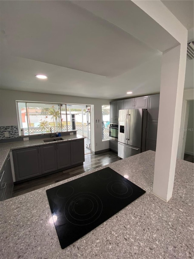 kitchen featuring a healthy amount of sunlight, high end fridge, sink, and gray cabinetry