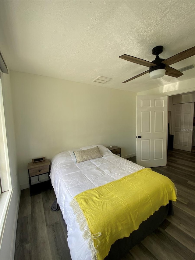 bedroom with ceiling fan, a textured ceiling, and dark hardwood / wood-style flooring