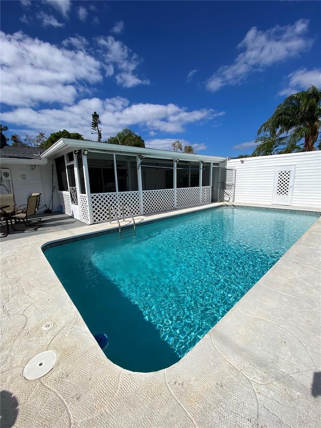 view of pool with a sunroom and a patio area