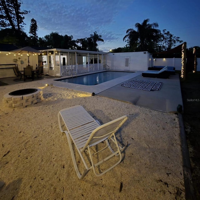 pool at dusk featuring a jacuzzi, a patio area, and a fire pit