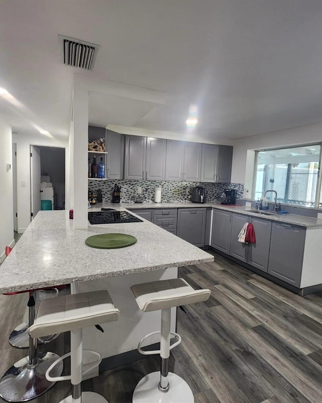 kitchen featuring sink, gray cabinets, a breakfast bar area, a kitchen island, and decorative backsplash