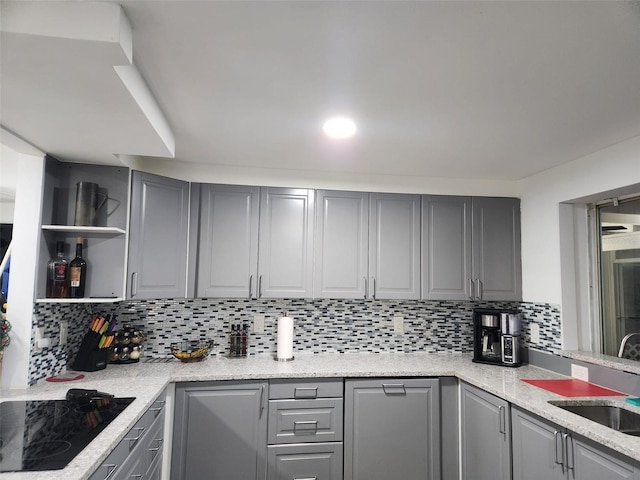 kitchen featuring sink, gray cabinets, black electric stovetop, light stone countertops, and decorative backsplash