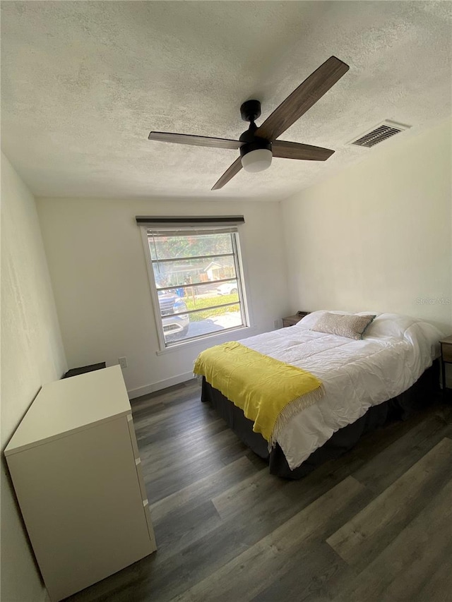 bedroom featuring ceiling fan, a textured ceiling, and dark hardwood / wood-style flooring