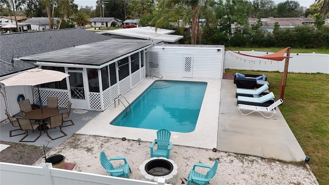 view of pool featuring a fire pit, a lawn, a sunroom, and a patio