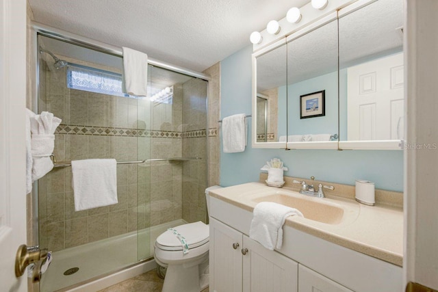 bathroom featuring a textured ceiling, tile patterned flooring, toilet, vanity, and a stall shower