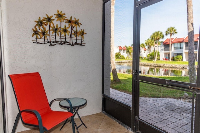 interior space featuring a water view, a textured wall, and light tile patterned floors